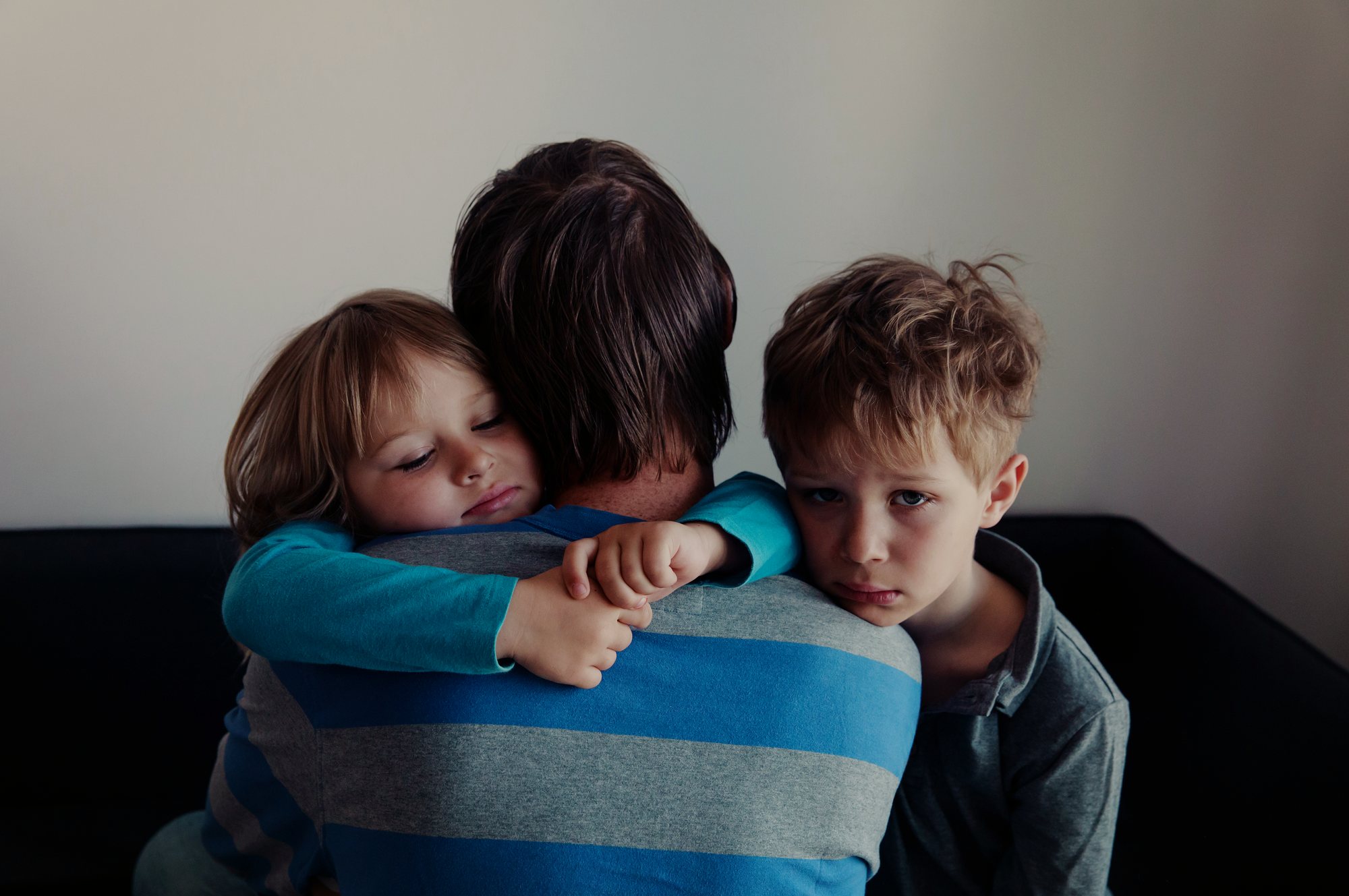 ایک ماں یا باپ دو بچوں کو گلے لگائے ہوئے
